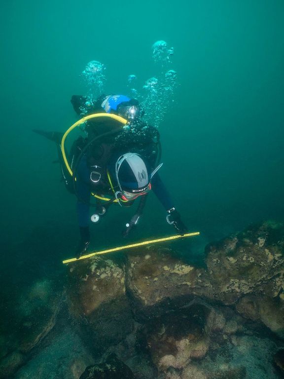 Underwater archaeologist inspecting a remaining wall of the submerged Maya city of Samabaj